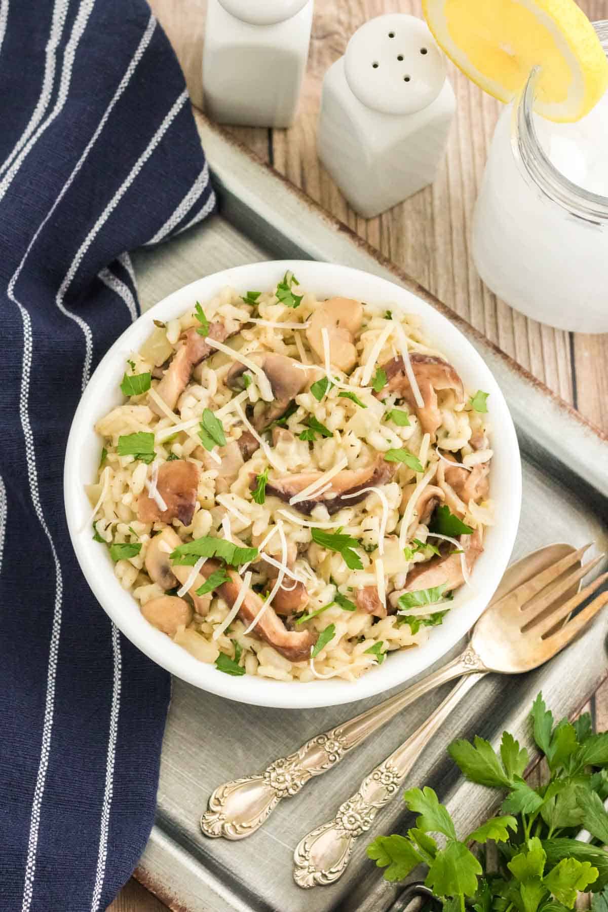 Overhead view of a bowl of Instant Pot mushroom risotto next to a glass of lemonade and a fork.