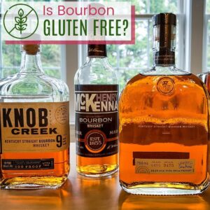 Bottles of Knob Creek, Henry McKenna, and Woodford Reserve Bourbon on a table in front of a window with a text overlay that says "Is Bourbon Gluten Free?".