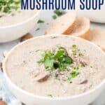 A bowl of cream of mushroom soup garnished with fresh parsley, next to slices of crusty bread and mushrooms with text overlay that says "Gluten Free Cream of Mushroom Soup"..