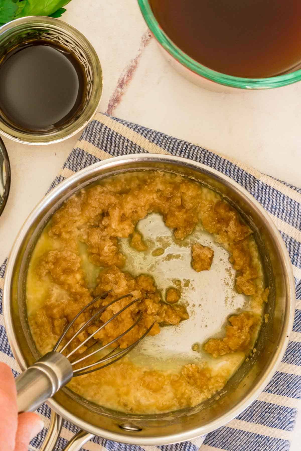 Melted butter and sweet rice flour is whisked together in a saucepan to form a roux.