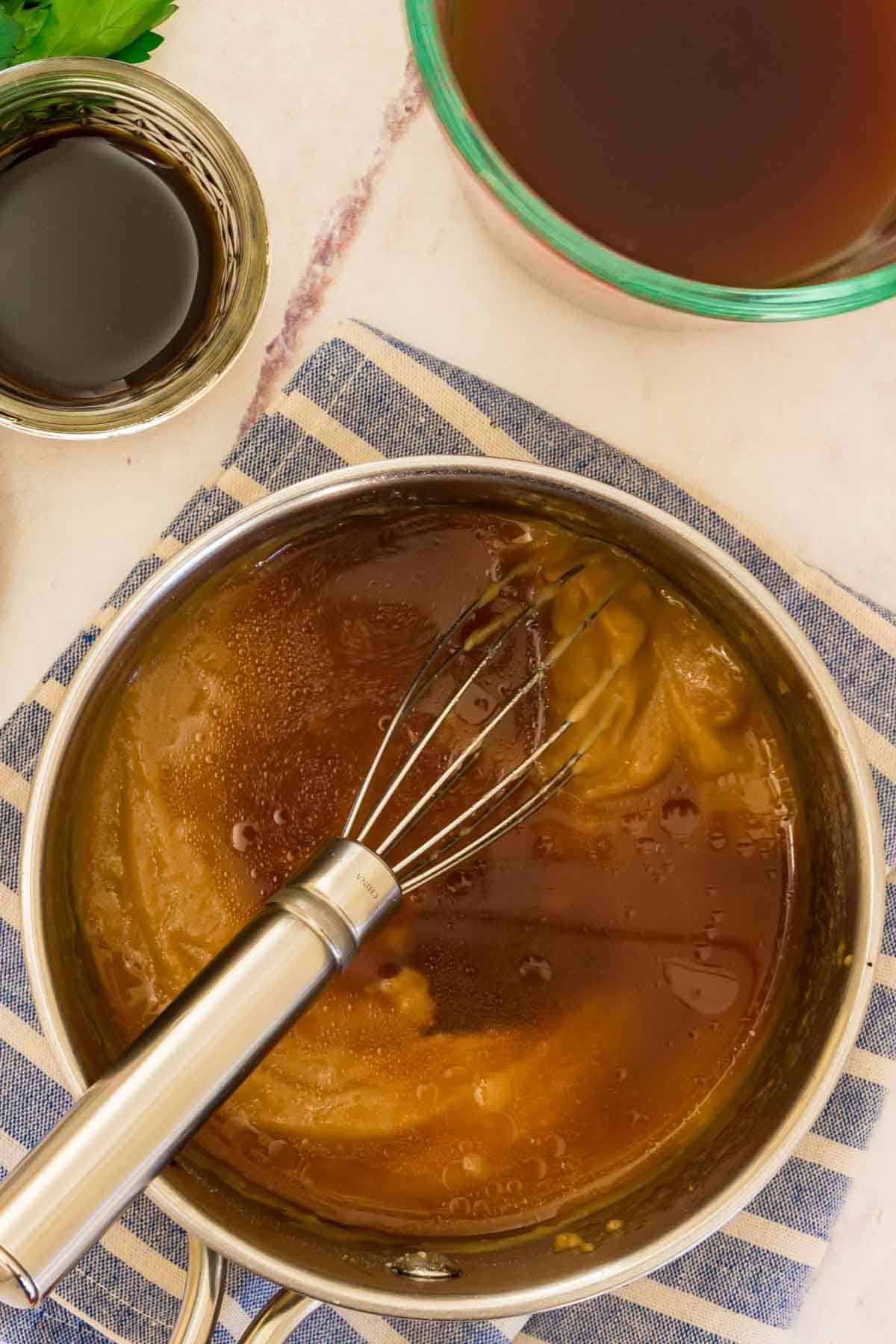 Beef broth is whisked into a saucepan of gluten-free brown gravy.