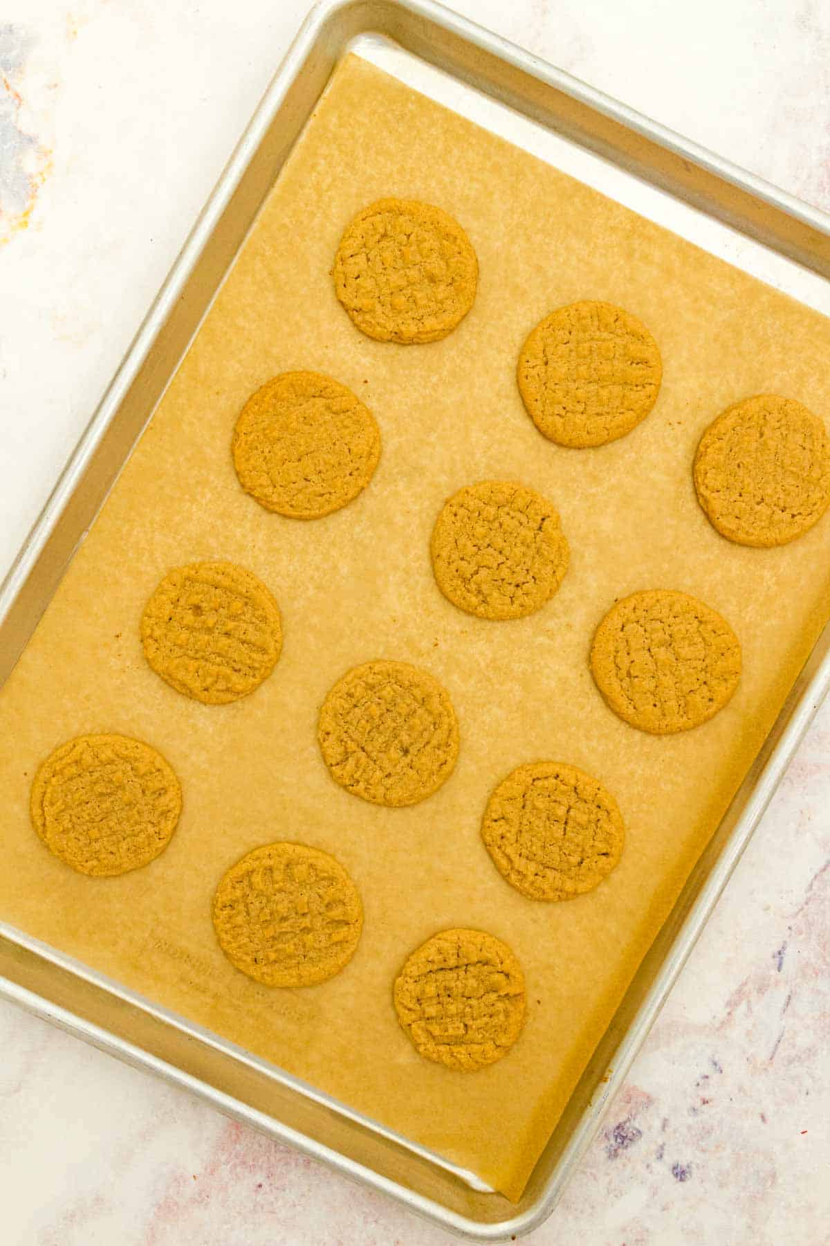 Baked gluten-free peanut butter cookies on a parchment-lined baking sheet.
