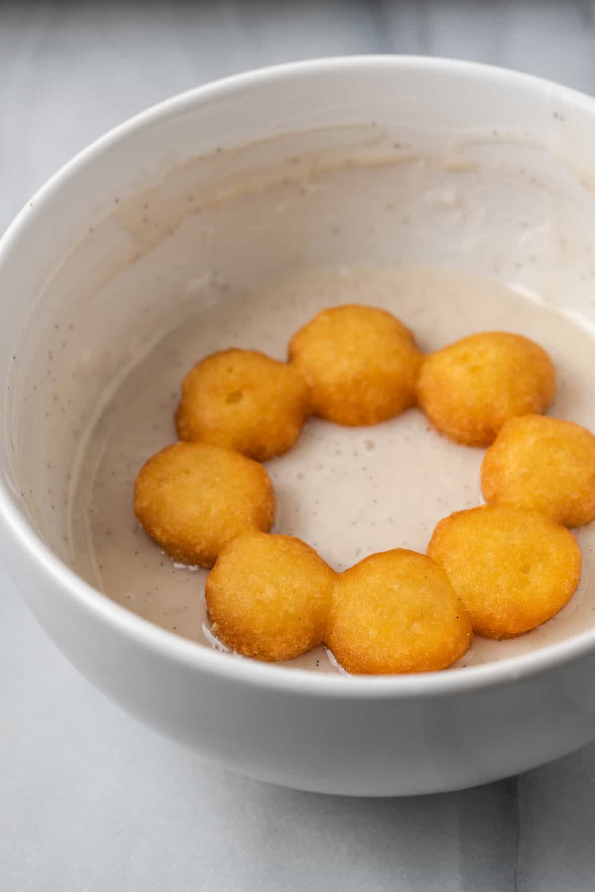 A gluten-free mochi donut deep frying in a skillet with oil.