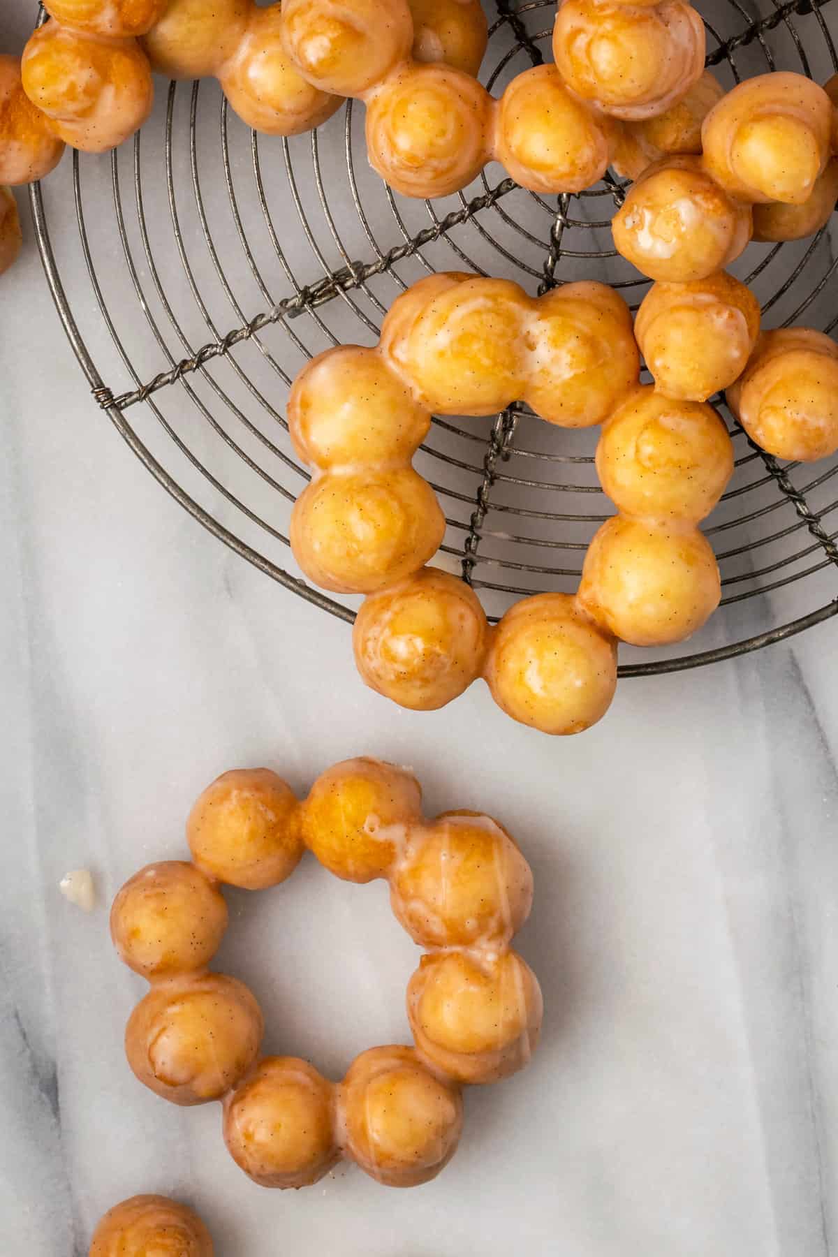 Fried gluten-free mochi donuts scattered over a wire rack.