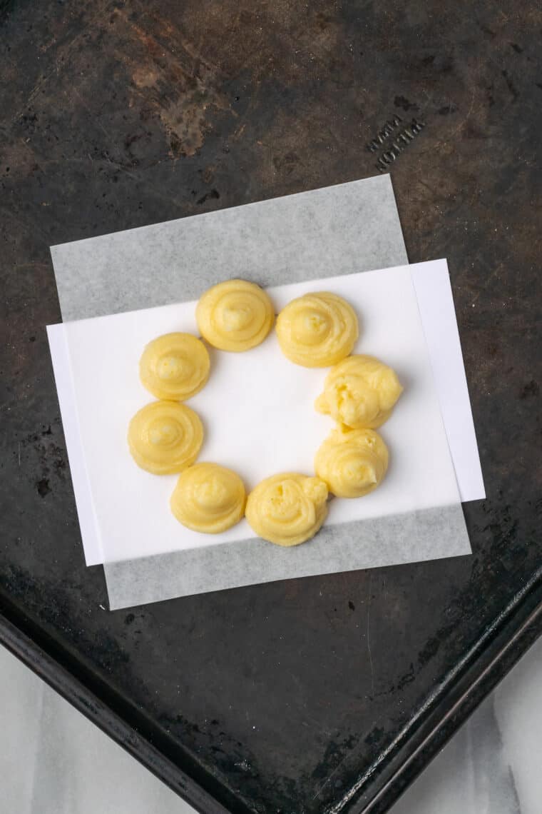 Gluten-free mochi donut batter piped onto a piece of parchment paper to form a "ring".