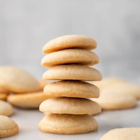 A stack of gluten-free vanilla wafers on a countertop, surrounded by more wafers.