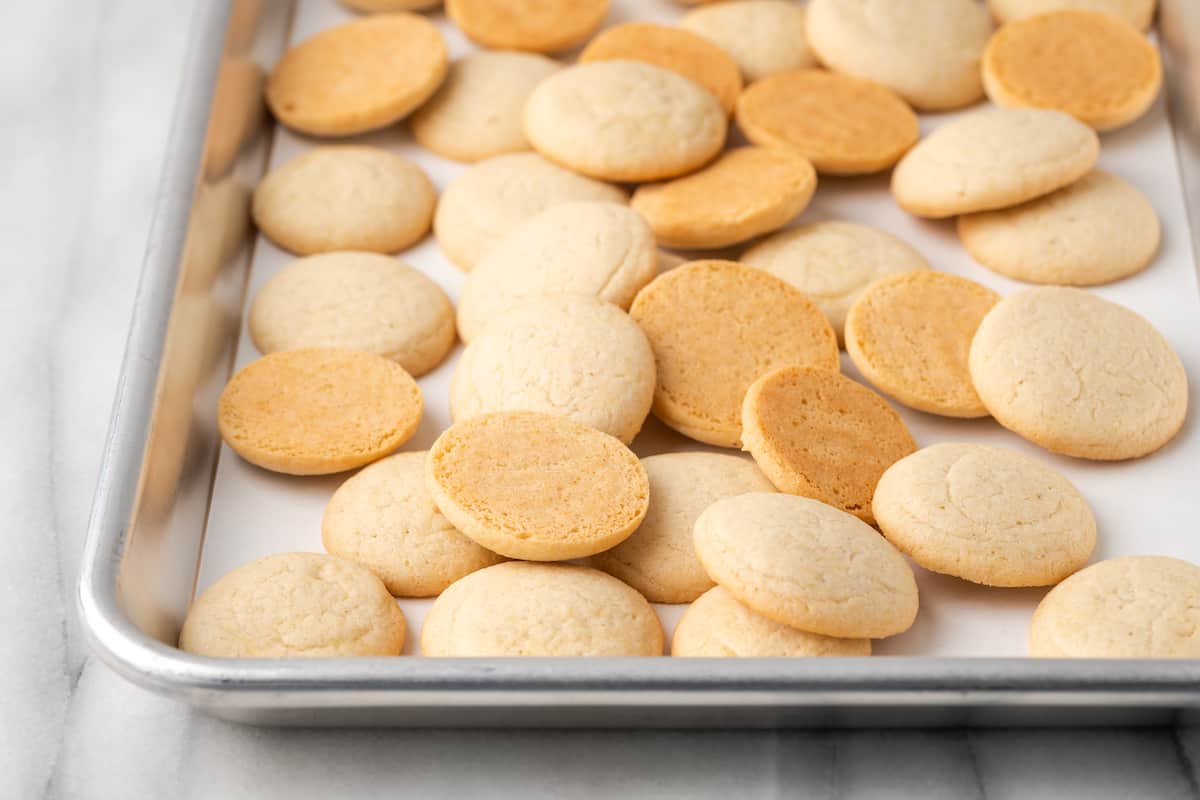 Assorted vanilla wafers on a metal baking sheet.