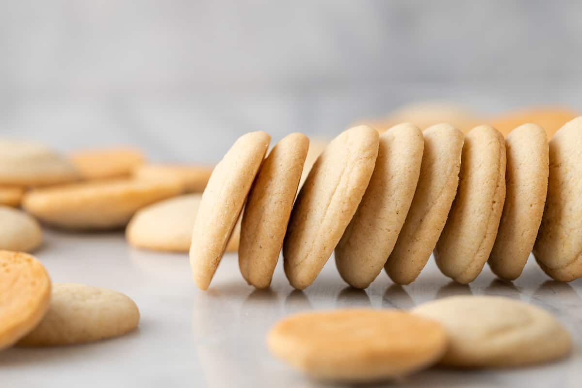 Gluten-free vanilla wafers stacked in a horizontal row, surrounded by more cookies.