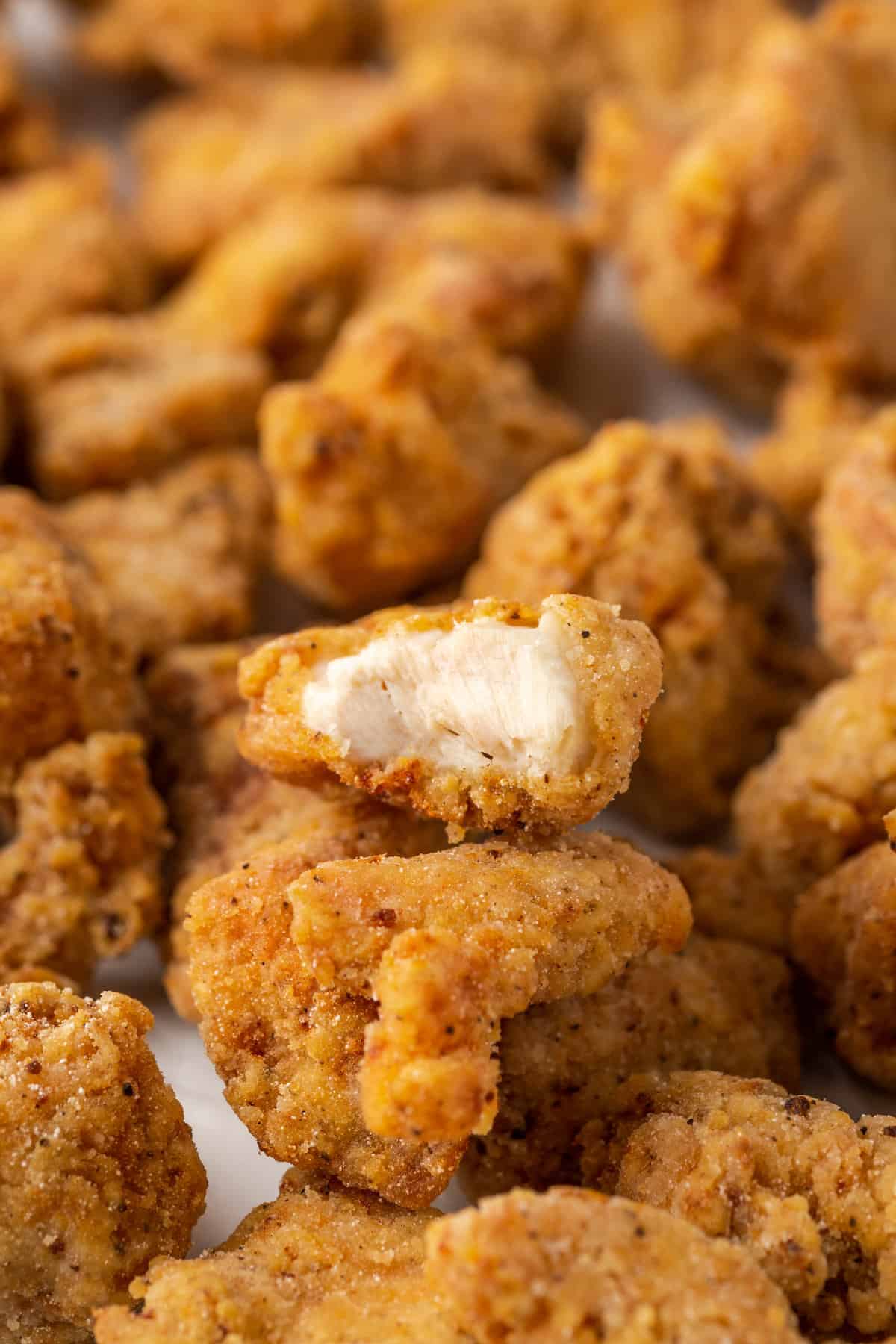 Assorted gluten-free KFC popcorn chicken with a bite missing from one nugget.