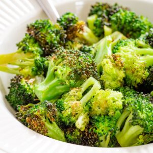 A bowl of bright green roasted broccoli.
