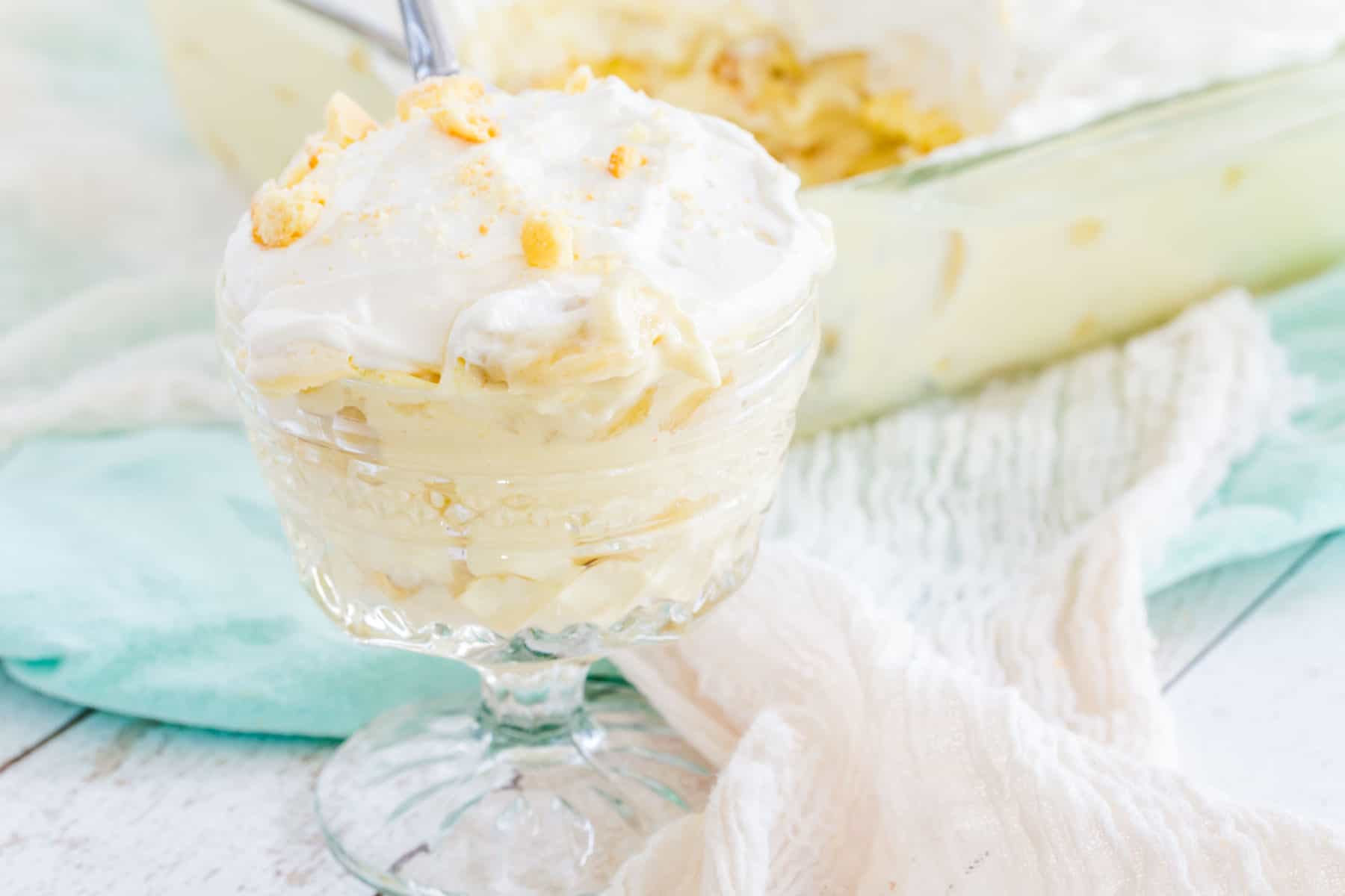 Gluten-free banana pudding served in a coup glass, with the remaining banana pudding in a casserole dish in the background.