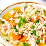 A bowl of hearty soup with orzo pasta, chicken, carrots, and peas with text overlay that says "Gluten Free Chicken Orzo Stew".