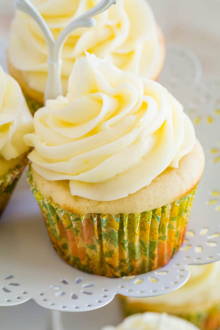A frosted gluten-free lemon cupcake on a cupcake stand.