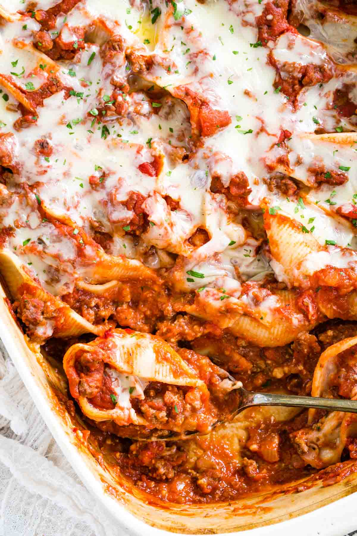 Gluten-free stuffed shells in a casserole dish with a serving missing from the corner.