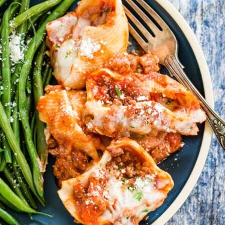 Overhead view of gluten-free stuffed shells served on a blue plate with green beans.