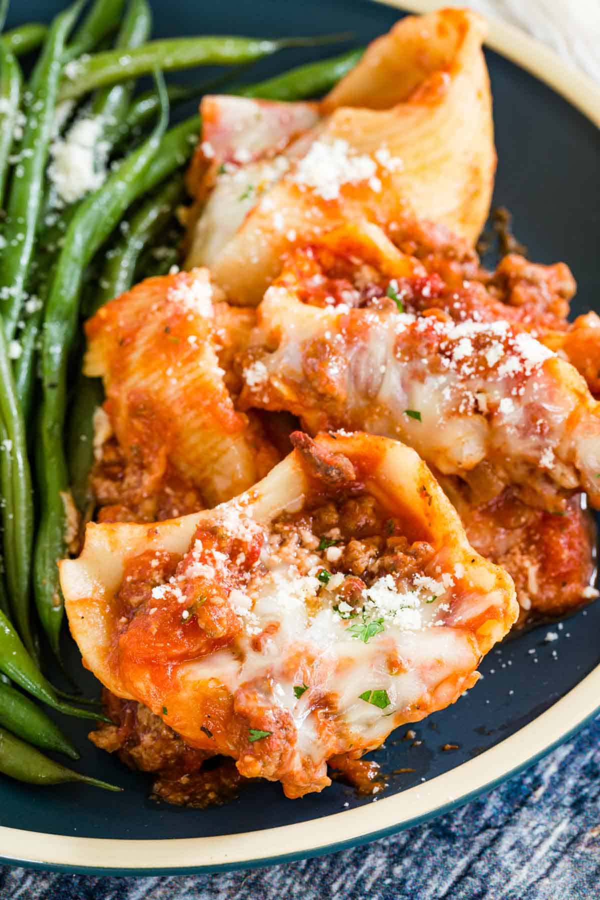 Gluten-free stuffed shells served on a blue plate with green beans.