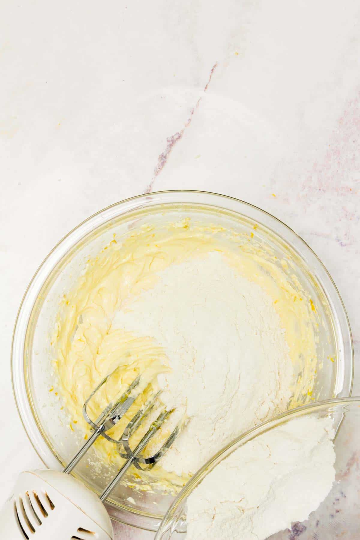 Dry ingredients are added to a mixing bowl with wet batter ingredients.