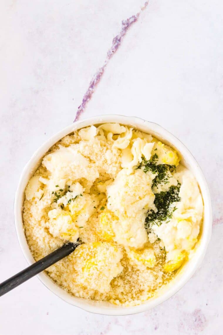 Ricotta, parmesan, and mozzarella cheese combined in a bowl with parsley.
