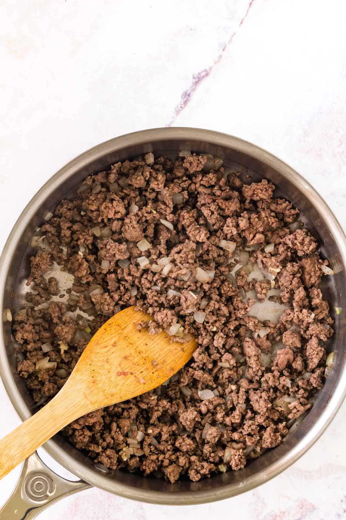 Browned ground beef and onions in a skillet.