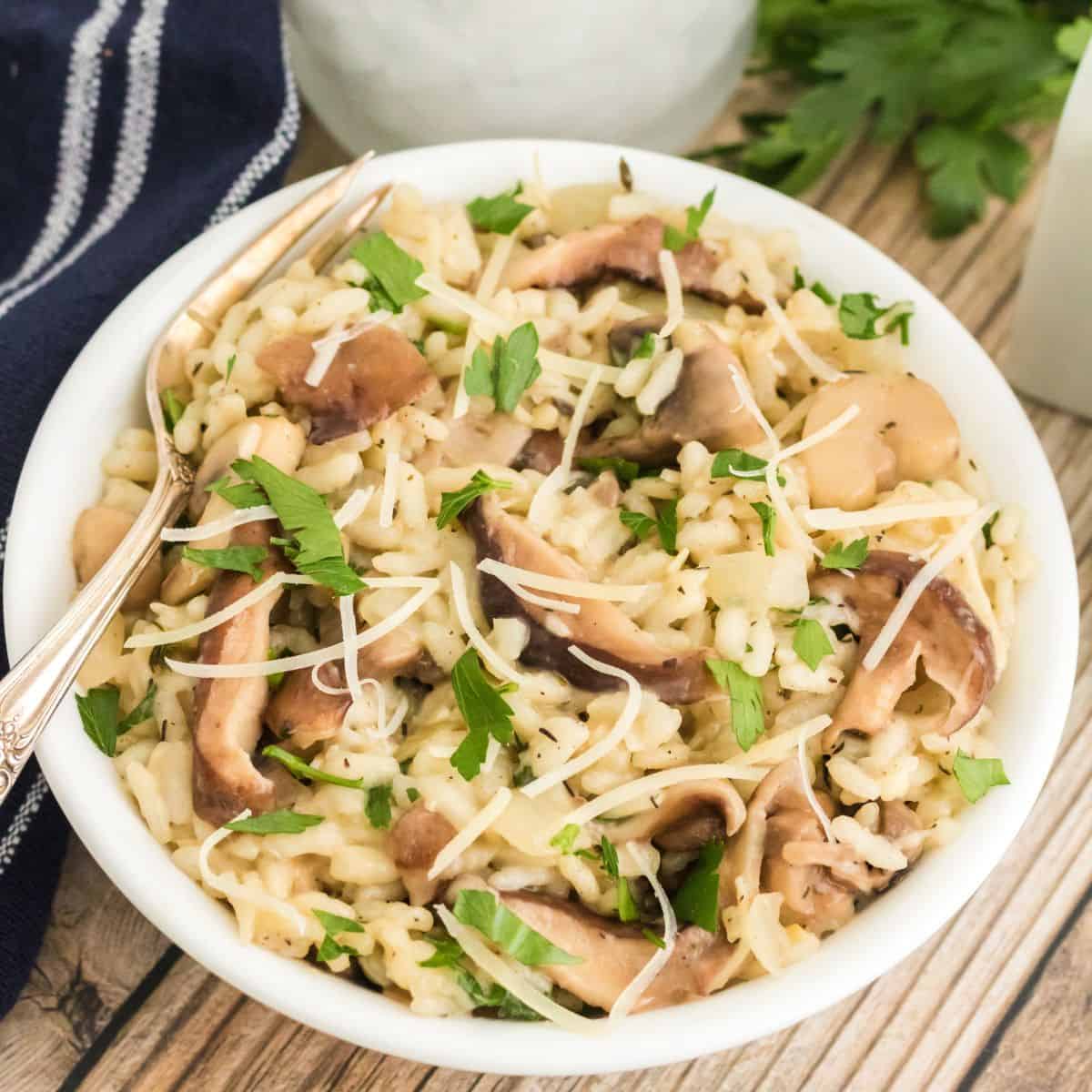 A bowl of mushroom risotto with a fork in it.