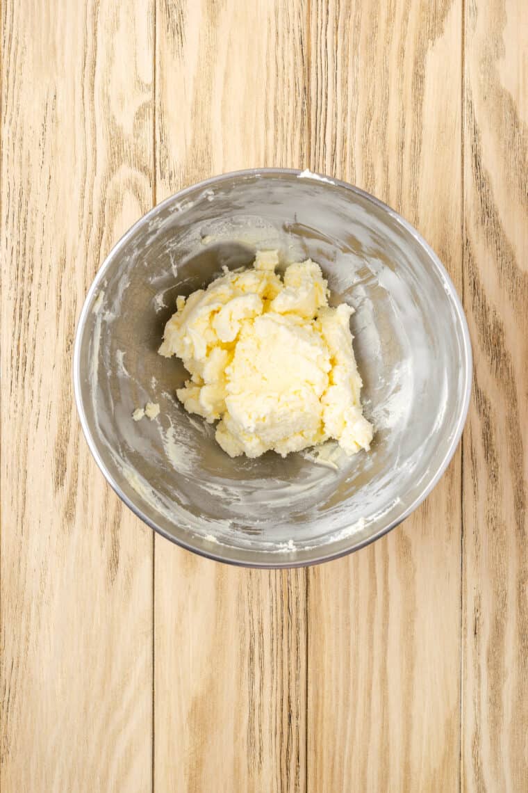 Butter and cream cheese combined in a metal mixing bowl.