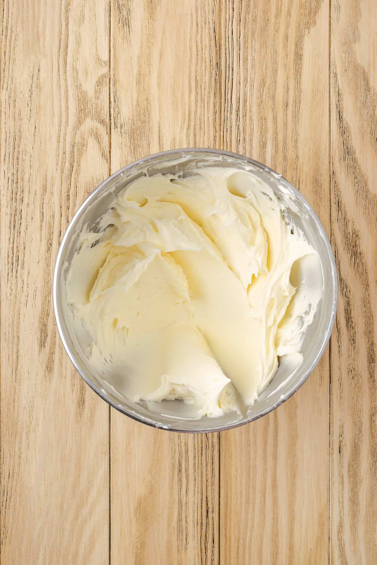 Cream cheese frosting in a metal mixing bowl.