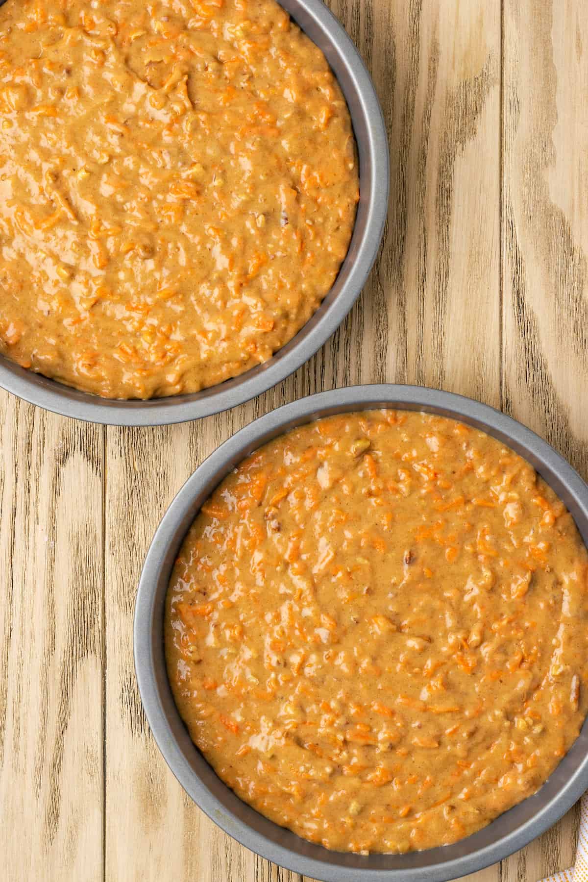 Gluten-free carrot cake batter divided between two round cake pans.