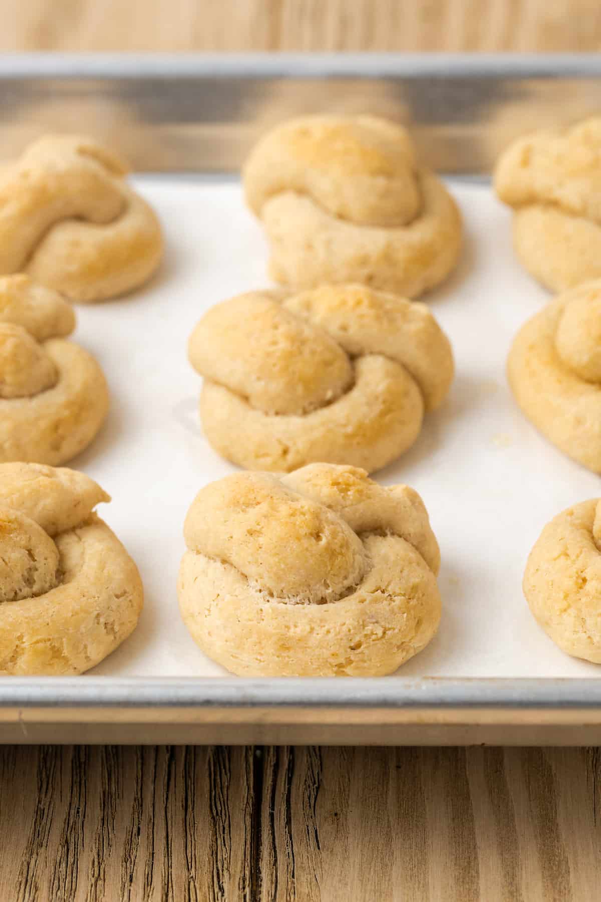 Gluten-free garlic knots on a parchment lined baking sheet.