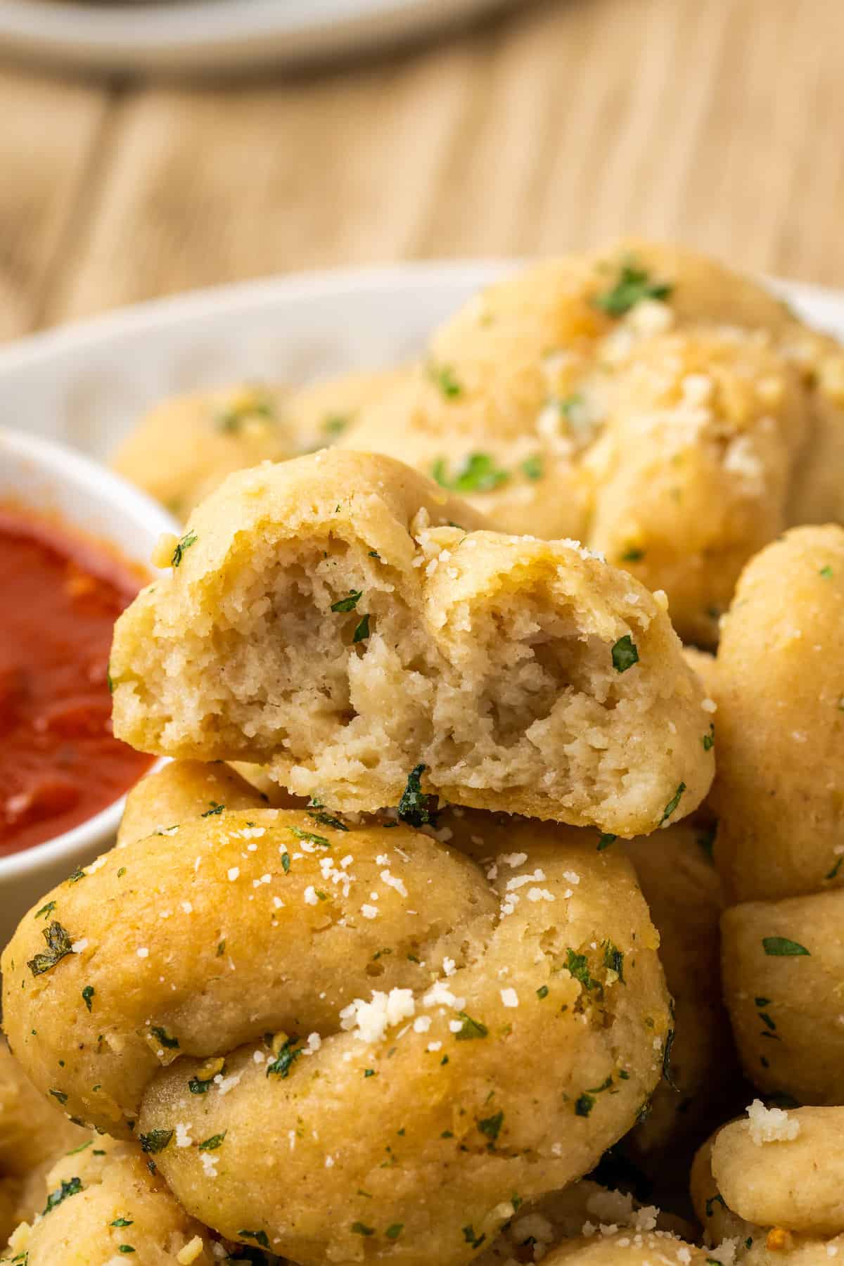 Close up of gluten-free garlic knots with a bite missing from one.
