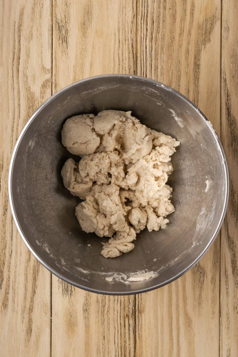 Shaggy gluten-free dough in a metal mixing bowl.