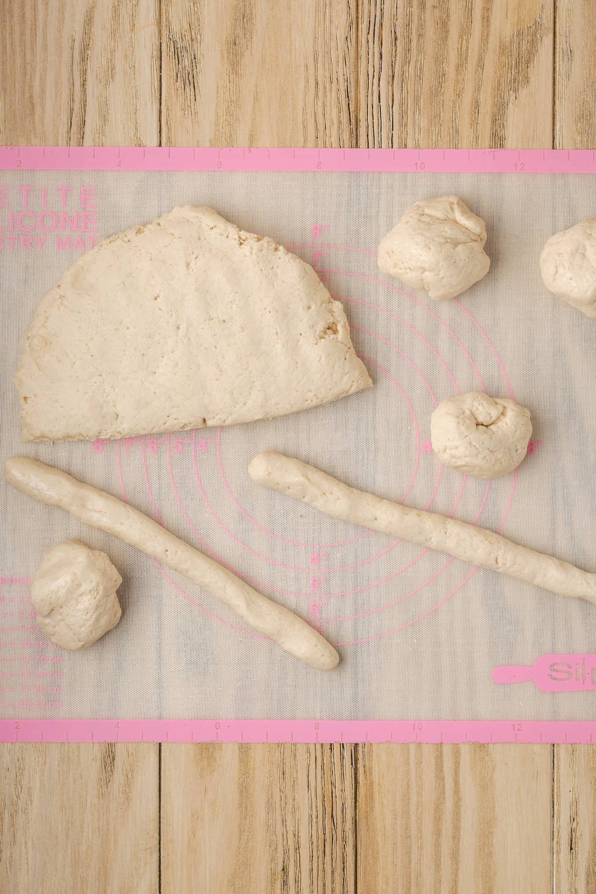 Dough portioned and shaped into balls and ropes on a silpat baking mat.
