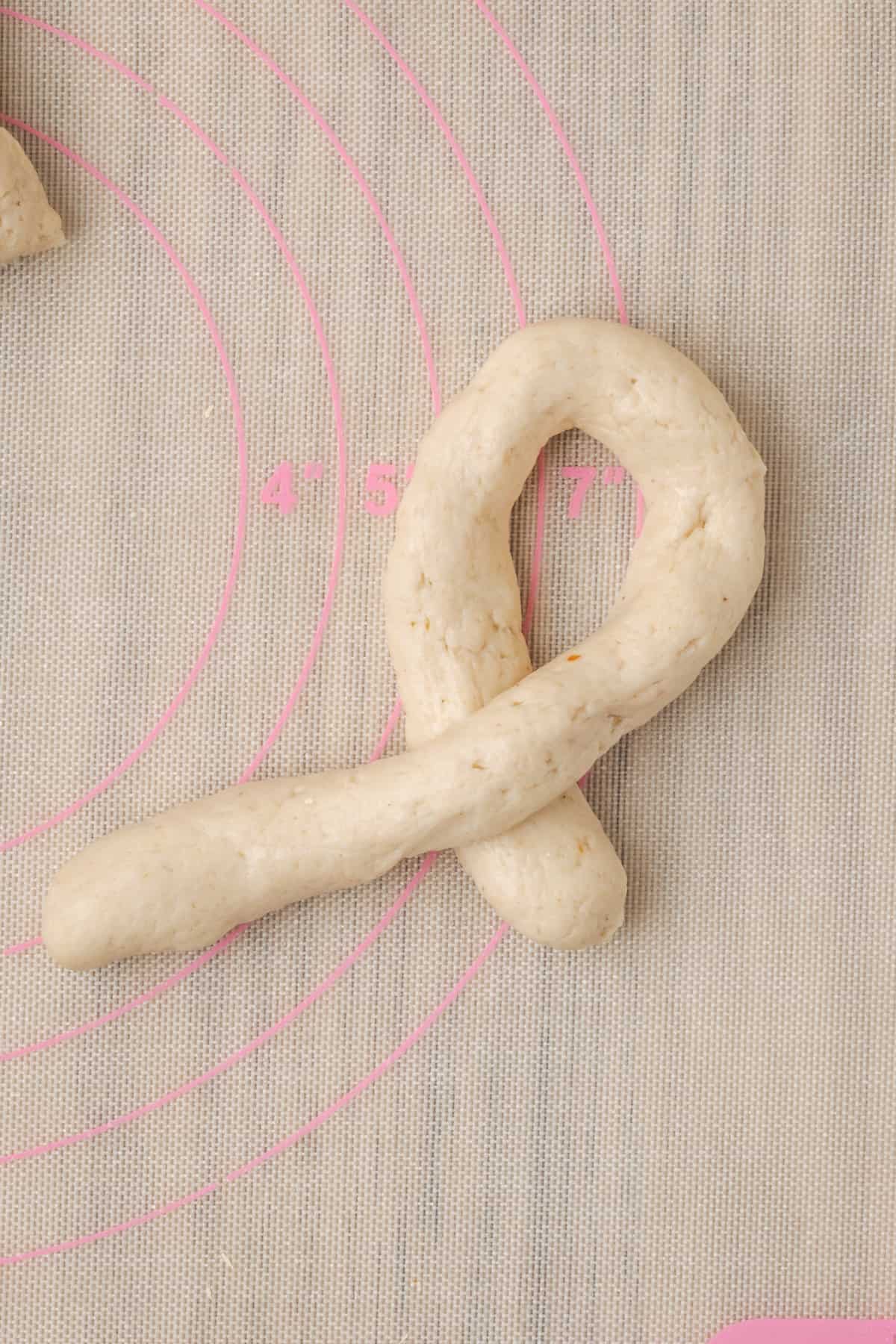 A rope of dough is partially folded over into a knot.