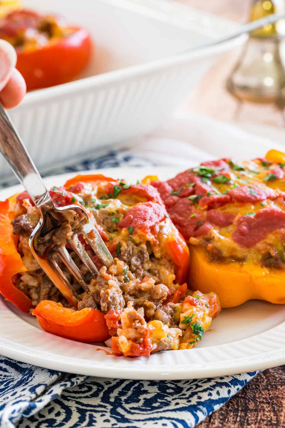 A fork scoops beef filling from a stuffed pepper on a white plate.