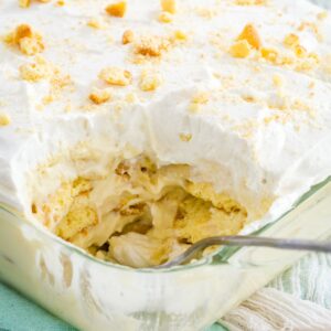 Gluten-free banana pudding in a casserole dish with a scoop missing from the corner and a spoon resting in the dish.