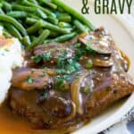 A cube steak smothered with brown gravy with mushrooms and onions on a plate with mashed potatoes and gravy with text overlay that says "Gluten Free Cube Steak & Gravy".