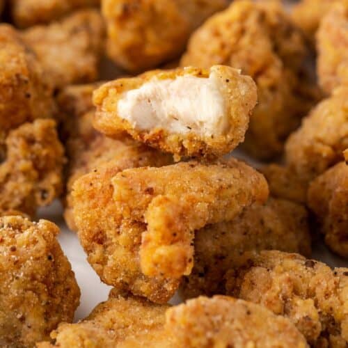 A closeup of pieces of popcorn chicken with a bite taken out of one.