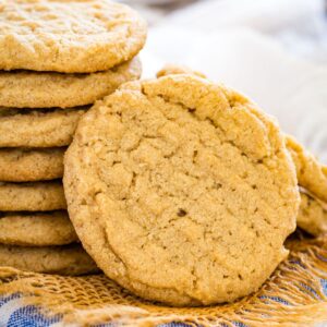 A peanut butter cookie leaning against a stack of more cookies.