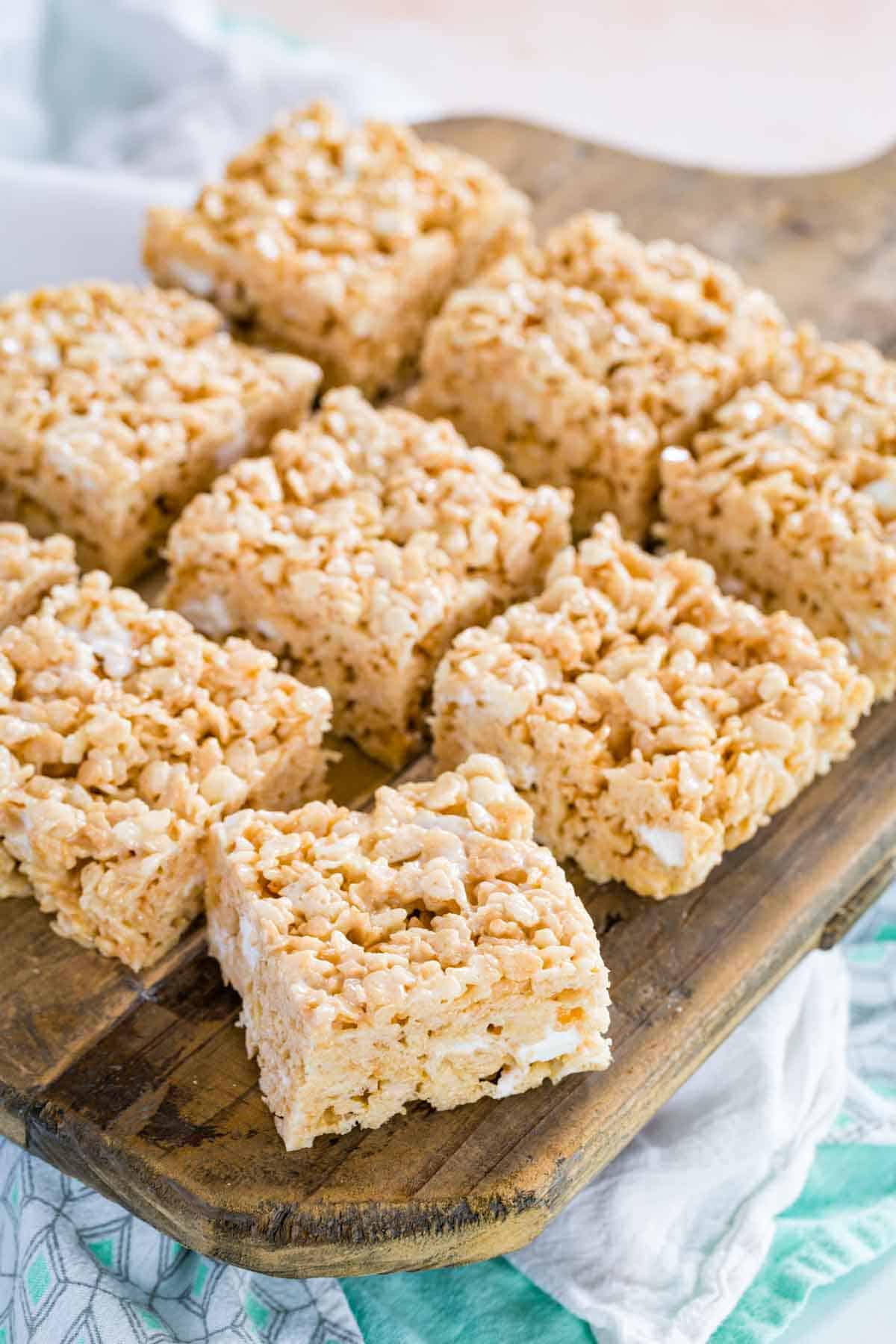 Assorted gluten-free rice krispies treats on a wooden platter.