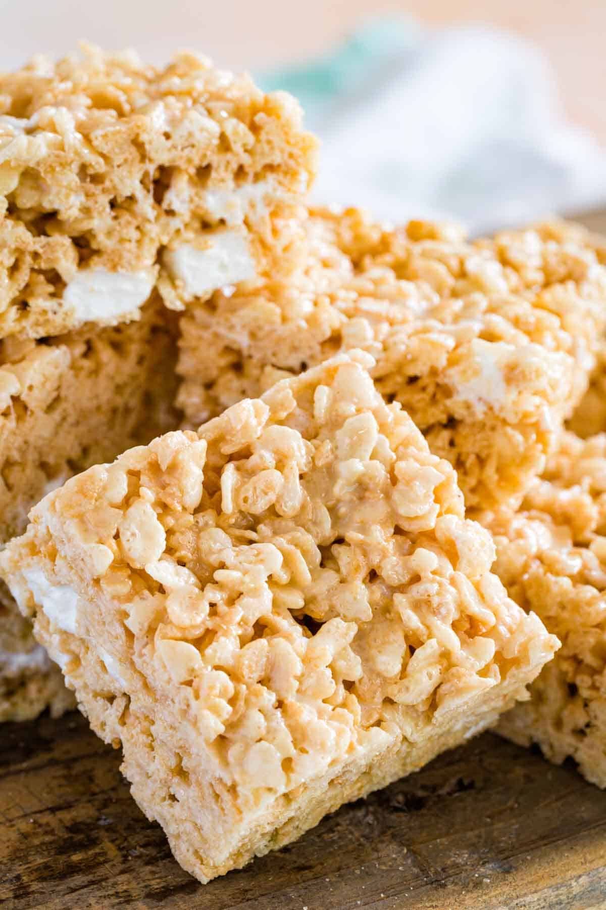 Assorted gluten-free rice krispies treats piled on a wooden board.
