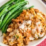 A serving of gluten-free skillet lasagna on a plate next to green beans.