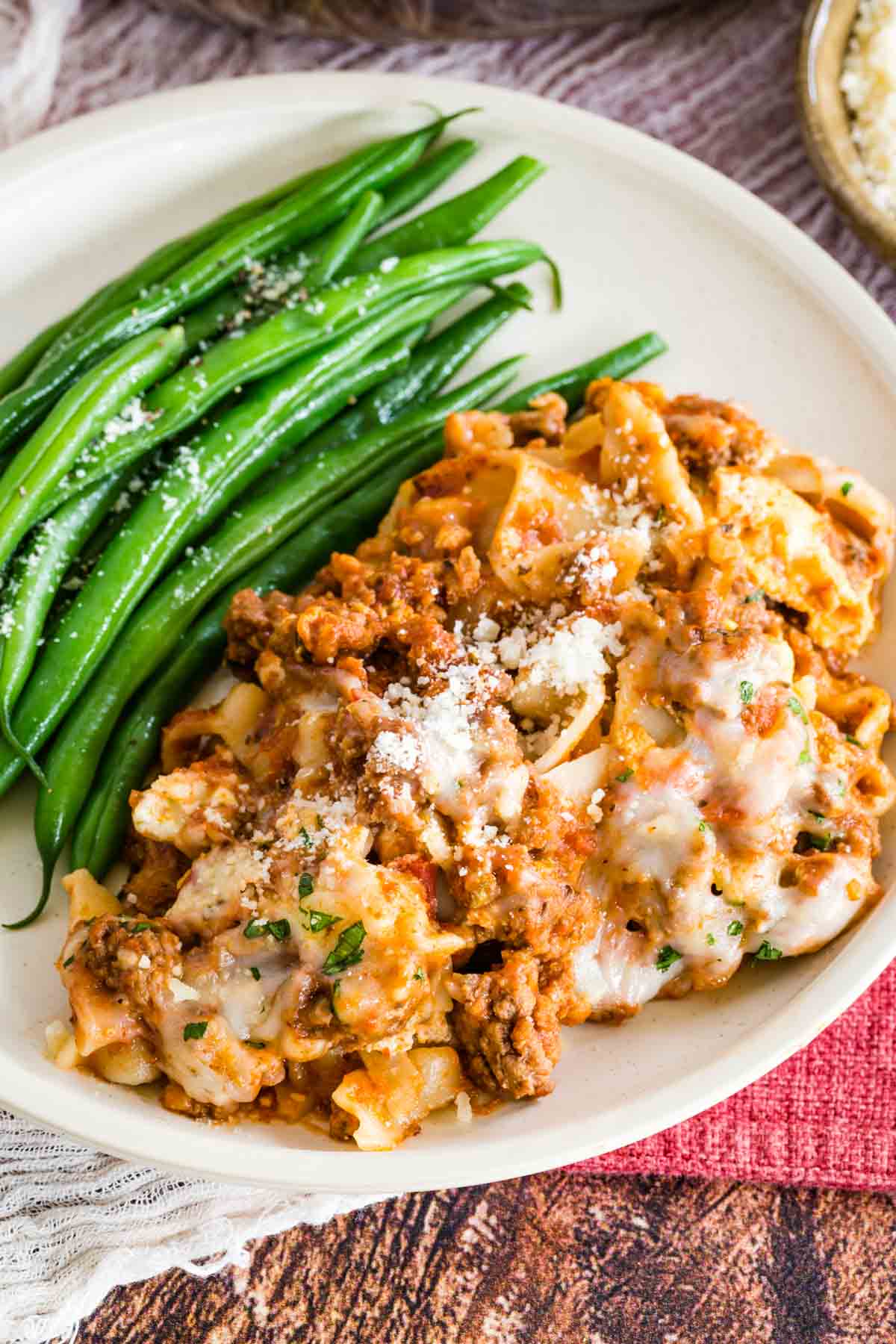 A serving of gluten-free skillet lasagna on a plate next to green beans.