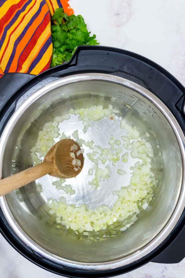 Onion and garlic sauteeing in the bottom of an instant pot.