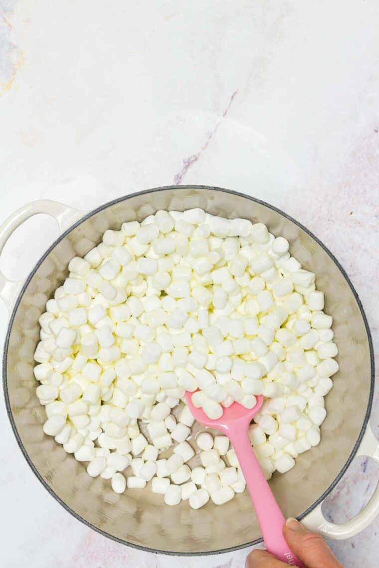 A bowl of mini marshmallows with a pink rubber spoon.