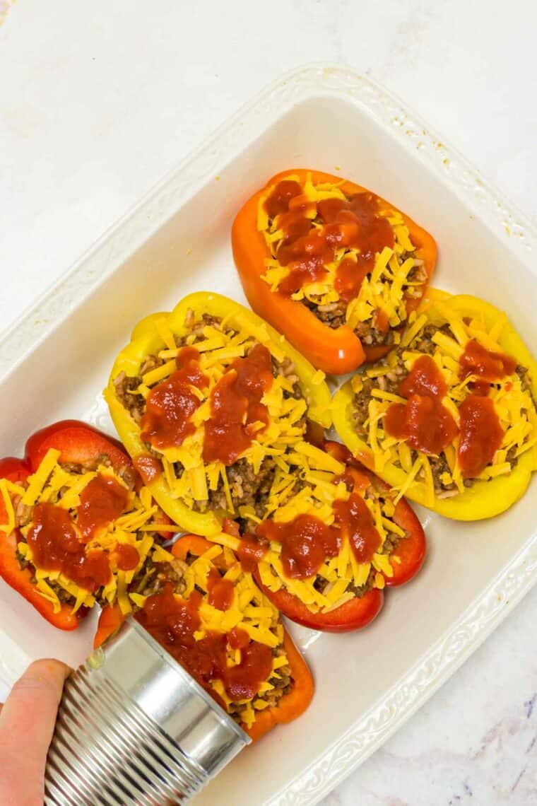 Bell peppers filled with a beef and rice mixture, topped with shredded cheese and tomato sauce.