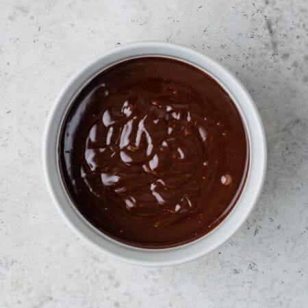 Overhead view of homemade chocolate glaze in a white bowl.