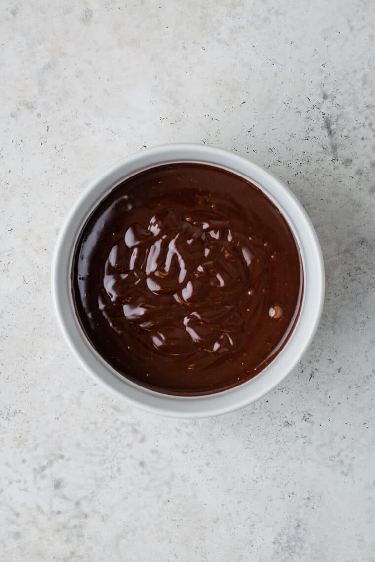 Overhead view of homemade chocolate glaze in a white bowl.