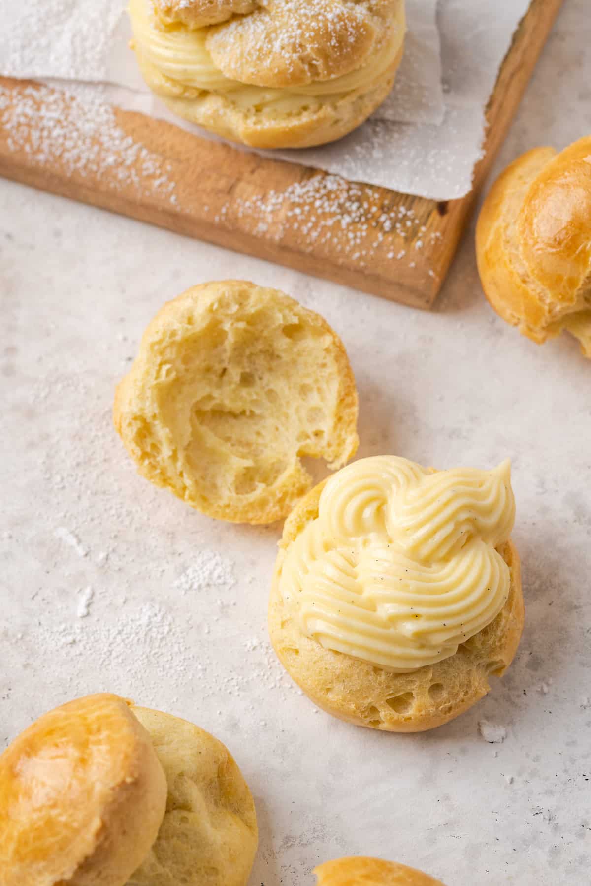 Overhead view of one half of a cream puff filled with vanilla pastry cream on a countertop.