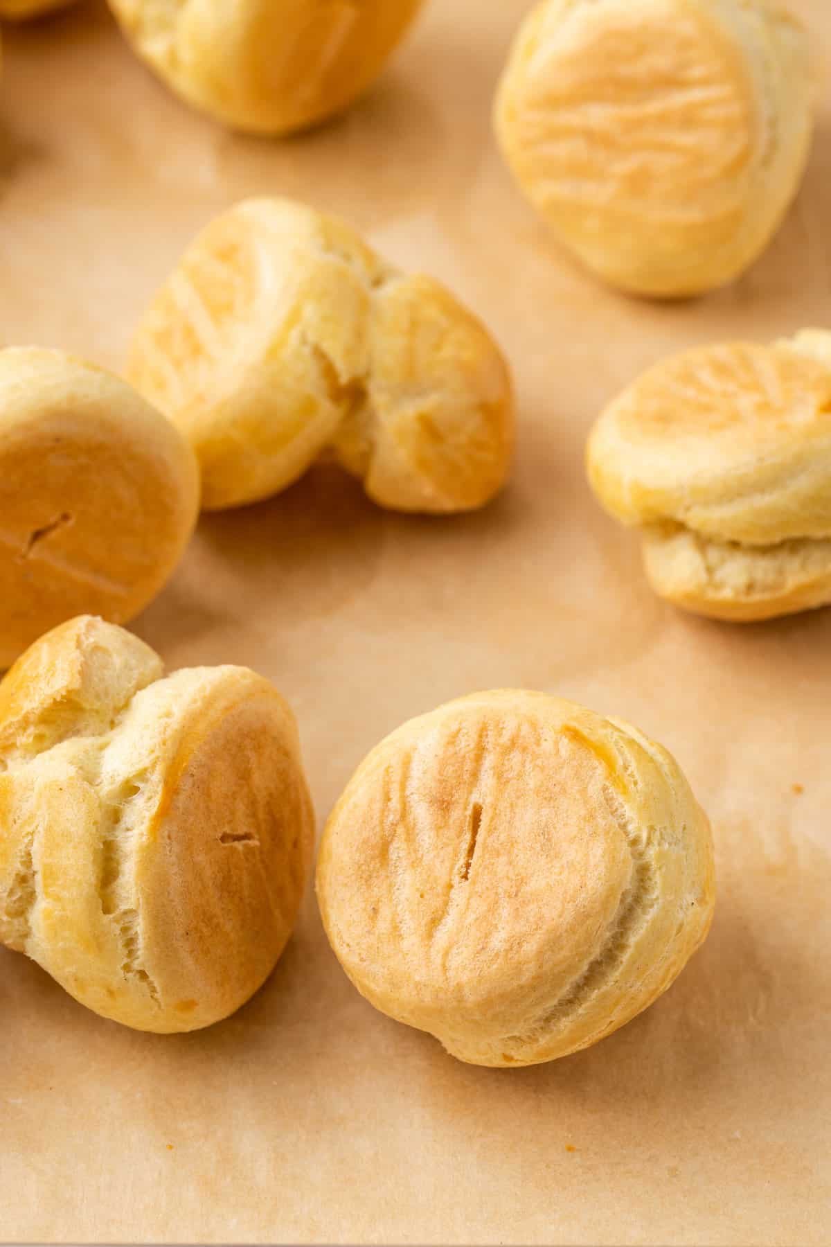 Assorted gluten-free cream puff pastries scattered on parchment paper.