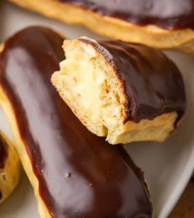 Close up of gluten-free eclairs on a white plate, with a bite missing from one.