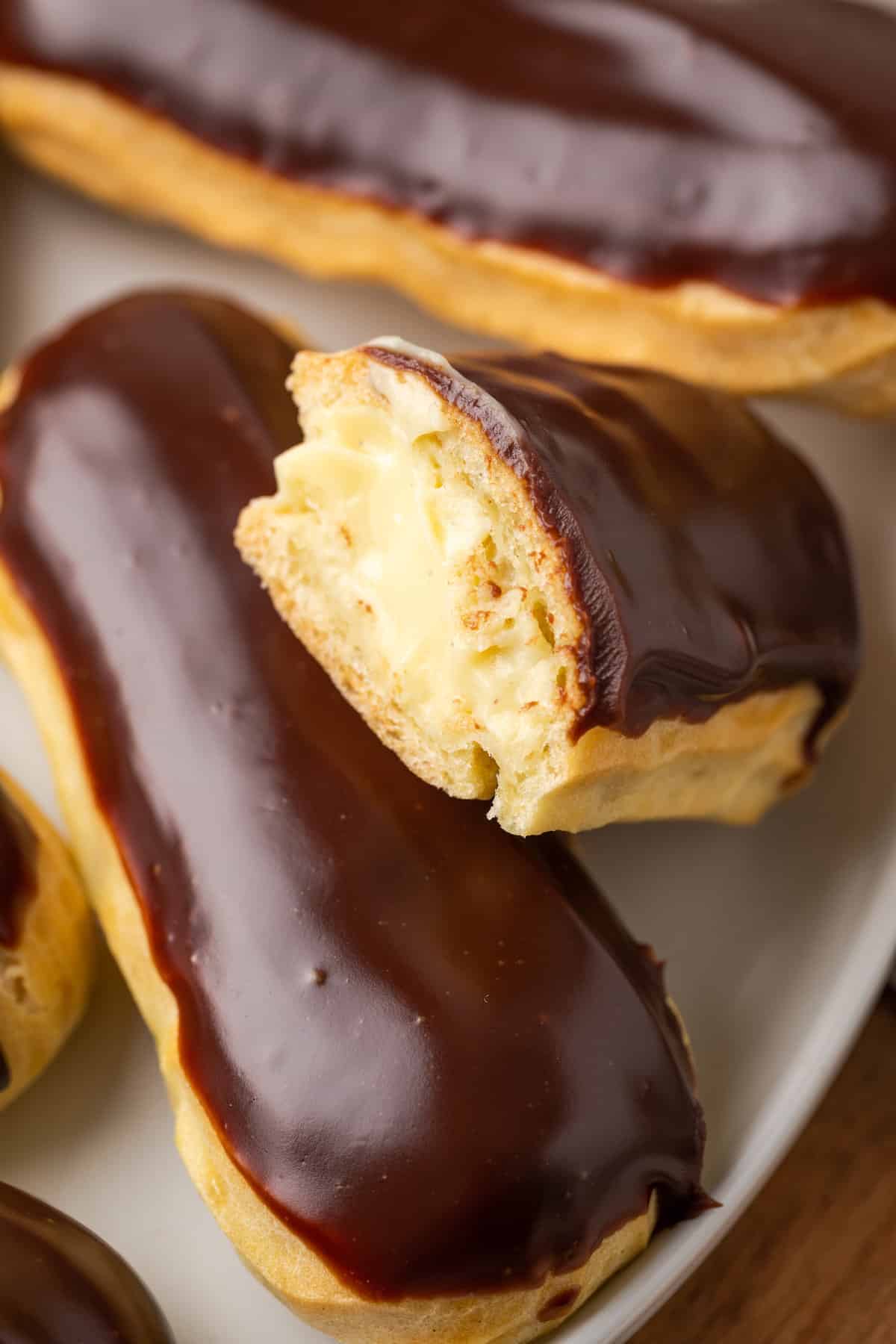 Close up of gluten-free eclairs on a white plate, with a bite missing from one.